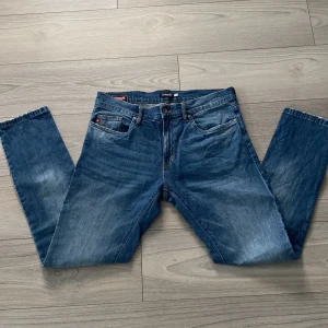 Blå tapered jeans från Big Star - Säljer ett par klassiska blå jeans från Big Star i tapered fit. Jeansen har fem fickor, snygga slitningar, fin design på bakfickorna och en washed out look.