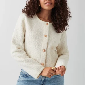 Vit cardigan jacka med guldknappar - Superfin vit cardigan jacka med rund halsringning och snygga guldiga knappar framtill. Perfekt att styla med jeans för en clean look. Perfekt nu inför hösten. Aldrig använd!