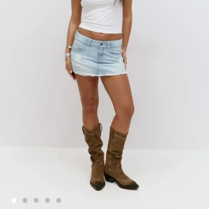 Ljusblå jeanskjol från gina  - Superkorta ljusblå jeanskjol med fransig rå kant och slitningar framtill. Klassisk femficksmodell med bälteshällor och dragkedja. Perfekta för dig som gillar en avslappnad och trendig look. Använd 1 gång