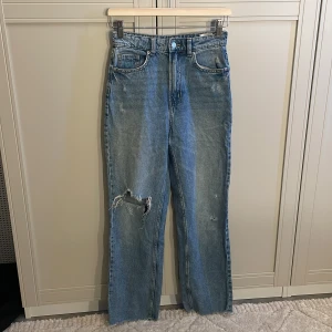 Jeans - Blåa högmidjade jeans med hål vid knänen. I storlek 34 från H&M 