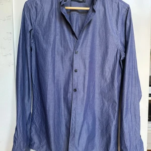 Blå skjorta från Peak Performance - Snygg blå skjorta från Peak Performance i 100% bomull. Klassisk modell med lång ärm, knappar framtill och krage. Perfekt för dig som gillar stilrena och enkla plagg med en modern touch.