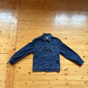Levi's klassisk jeansjacka blå L - Säljer en klassisk blå jeansjacka från Levi's i storlek L. Jackan har raka linjer, två bröstfickor med knappar och snygga söm-detaljer. Perfekt för dig som gillar tidlös denimstil och vill ha en ikonisk jacka i garderoben. Köpt i en vintage butik Nederländerna för ca 70€.