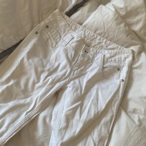 Vita bootcut jeans  - Snygga vita jeans med bootcut passform. Klassisk femficksmodell med silverfärgade nitar och knapp. Insidan av linningen har ett blommigt tyg som detalj. Perfekta för dig som vill ha en fräsch och stilren look.