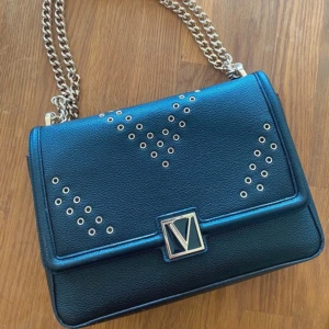 Victoria’s Secret väska - En väska från Victoria’s Secret, köpt för 800kr är en del använd men fortfarande i fint skick. Bandet/kedjan går att justera så man antingen kan ha den under armen eller över axeln.