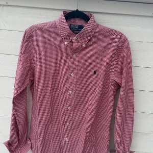 Ralph Lauren skjorta - Snygg röd- och vitrutig skjorta från Polo Ralph Lauren i slim fit-modell. Skjortan är i storlek m, priset är 399kr men kan diskuteras. Skjortan är i bra skick!