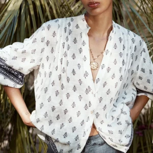 Vit mönstrad blus från Zara XS - Luftig vit blus från Zara i bomull med blått mönster och dekorativa detaljer på ärmar och nederkant. Skjortan har lång ärm, knappar framtill och avslappnad passform. Blusen är ny med lappen kvar.