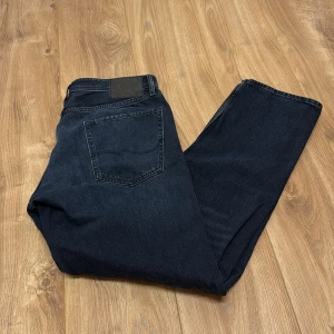 Mörkblå jeans från Jack & Jones - Snygga mörkblå jeans från Jack & Jones med klassisk femficksdesign och rak passform. Jeansen är tillverkade i bomull och har en stilren look som funkar till det mesta. Perfekta för dig som gillar en enkel och tidlös stil.