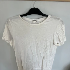 Vit basic t-shirt från Monki - En klassisk vit t-shirt från Monki i storlek S. Modellen är enkel med rund halsringning och korta ärmar. Tillverkad i mjuk bomull som känns skön mot huden. Perfekt att styla med jeans eller kjol för en clean look. Har ett pyttelitet hål men det syns inte när man har på sig den. Använd fåtal gånger. 