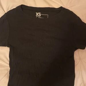 Svart ribbad t-shirt  - En svart ribbad t-shirt från new Yorker i storlek XS. T-shirten har korta ärmar och rund halsringning. Enkel och stilren modell som passar till det mesta!!🥰🥰