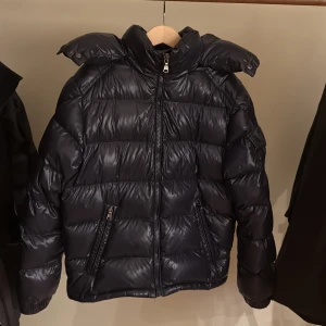 Moncler Maya - En stilren Moncler Maya i toppskick, den enda defekten är att hängaren är sönder men inget som man märker. Det är storlek 10-12 år beroende på längd. Priset är inte inristat i sten! 
