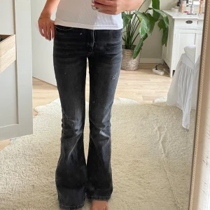 Svarta bootcut jeans från Levis - Säljer ett par svarta Levis jeans med bootcut passform. Jeansen har klassisk femficksdesign, låg midja och lätt utsvängda ben. Materialet är jeans i bomull och färgen är tvättad svart med en cool, lite sliten look.