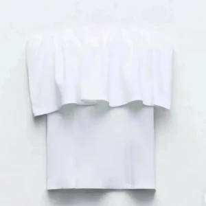 Vit volangtopp zara - Populär superfräsch vit tubtopp med volangdetalj upptill. Axelbandslös bandeau-modell som sitter snyggt och ger en clean look. Perfekt till jeans eller kjol för en trendig stil. Gjord i mjukt bomullstyg som känns skönt mot huden. Är i storlek L men sitter som en M😊