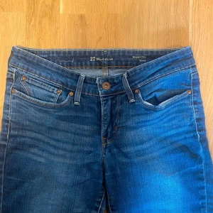 Levi's skinny jeans blå midwaist - Snygga blå skinny jeans från Levi's med klassiska fem fickor och snygga slitningar. Modellen är midwaist och har en smal passform som sitter tajt hela vägen ner. Perfekta till sneakers eller boots och funkar året runt.