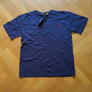 Marinblå t-shirt från Polo Ralph Lauren - Säljer min oanvända tröja från Ralph Lauren då jag inte kunde ha den.