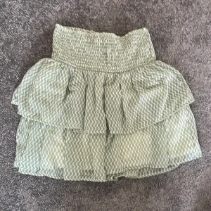 Grön volangkjol med vågigt mönster - Söt kortkjol i ljusgrönt med vågigt mönster och volanger. Kjolen har smock i midjan för en bekväm passform och är gjord i ett lätt, luftigt material. Använd cirka 3 gånger bara💗