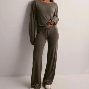 Brunt mjukisset - Säljer ett par bruna mjukisbyxor med breda ben och dragsko i midjan. Byxorna har en loose fit och är tillverkade i ett mjukt, stretchigt material som känns riktigt skönt mot huden. Perfekta för chill dagar eller när du vill vara bekväm men ändå se snygg ut. Säljer också matchande tröja till, tillsammans. 300 för hela sättet. 