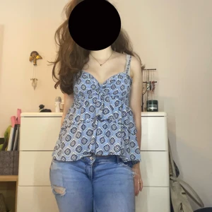 Blå mönstrad linnetopp med volang - Supersöt blå linnetopp med vitt och mörkblått grafiskt mönster. Toppen har smala axelband, v-ringning och volangig, flowy passform som ger en luftig känsla. Toppen är ifrån Gina Tricot men jag har då sytt om den så att den passar min stil bättre. Toppen är i storlek xs ❤️❤️
