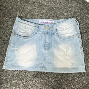 Ljusblå jeanskjol  - Snygg ljusblå jeanskjol från Goodies med slitna detaljer och fina fickor både fram och . Säljer då den börjar bli för liten. Midjemått: 70cm + stretch bar. längd: 28cm