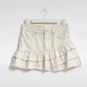 Vit jeanskjol med volanger - Supersöt beige jeanskjol med volanger från Gina Tricot. Perfekt för dig som vill ha en lekfull och cool stil. Stl 36 köptes förra sommaren, går inte längre att köpa, aldrig använda så helt ny skick, säljes då de var för små💕