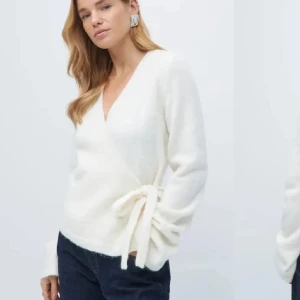 Vit omlottkofta med knytband - Superfin vit omlottkofta med v-ringning och knytband i sidan. Koftan har långa ärmar och är stickad i ett mjukt material som känns riktigt cozy. Perfekt att slänga på sig över ett linne eller t-shirt för en chill look.