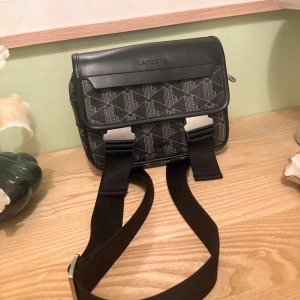 Lacoste Axelremsväska  - Hej! Säljer min Lacoste Axelrems väska i väldigt bra skick, ny pris ligger på 2 000 kr och säljs av mig nu för 895 kr, kvitto finns. Hör av er vid intresse!