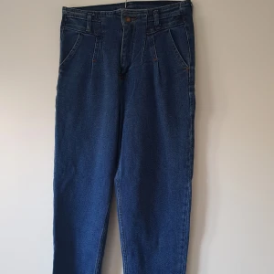 Blå mom jeans från Rich Star, W26 - Snygga blå mom jeans från Rich Star med klassisk hög midja och raka ben. Jeansen har framfickor med veck, bälteshällor och bakfickor. Tillverkade i robust denim med orangea sömmar för en retro vibe.  Helt & fint skick