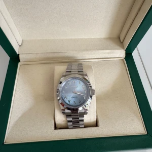 Silverfärgad Seiko automatisk klocka - Snygg Seiko automatisk klocka med silverfärgat armband i metall och ljusblå urtavla med subtilt mönster. Klassisk rund boett och stilrena index. Perfekt accessoar för dig som gillar stilren design och kvalitetskänsla.
