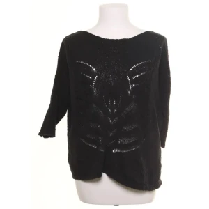 Stickad tröja med hålmönster och loose fit - Svart stickad tröja från Flash Woman med coolt hålmönster framtill. Tröjan har trekvartsärm och en lite lösare passform. Perfekt för dig som gillar en avslappnad stil. Med rätt accessoarer kan den även vara rätt edgy.