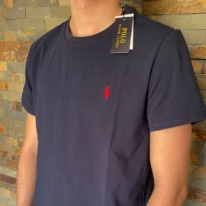 Ralph lauren T-shirt - Jag säljer en riktig snygg blå polo Ralph Lauren T-shirt. Denna mörkblå T-shirten är väldigt många ute efter och nu är den perfekt till sommaren. Skicket på denna är helt nytt och den är fantastisk, 10/10. Storleken är M. Priset jag kommer sälja denna för är 399kr men kan sänka priset vid snabb affär. Kom med prisförslag. Kontakta mig vid några funderingar eller frågor. Mvh