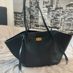 Svart stor handväska Gina tricot - Stilren svart axelväska i skinn med breda vingar och snygg guldfärgad låsdetalj framtill. Lite sliten på axelbandet