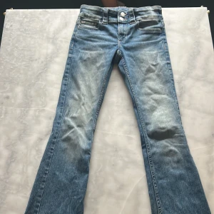 Blå bootcut jeans från H&M, låg midja - Snygga blå bootcut jeans från H&M med låg midja och justerbar midja. Jeansen har klassisk femficksdesign, slitningar framtill och bakfickor. Perfekta för dig som gillar en avslappnad och trendig look.💗💞