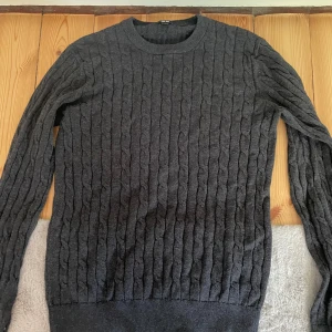 Mörkgrå kabelstickad tröja Uniqlo - Säljer en mörkgrå kabelstickad tröja från Uniqlo i storlek S. Tröjan har rund halsringning, lång ärm och klassiskt kabelmönster. Perfekt för lager-på-lager och chill höst- eller vinterstil.