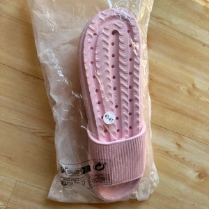 Ljusrosa sandaler i syntet - Snygga ljusrosa sandaler med ribbad rem och perforerad sula för extra ventilation. Tillverkade i lätt syntetmaterial, perfekta för sommardagar eller efter träning. Enkel slip-on-modell med platt sula och öppen tå.