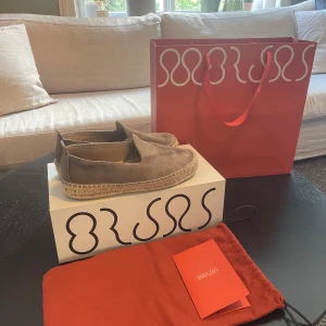 Taupe espadrillos i mocka från Morjas - Snygga taupefärgade espadrillos från Morjas i mocka. Skorna har en klassisk rund tå och grov flätad sula i naturmaterial som ger en chill vibe. Perfekta för sommaren och lätta att matcha med både shorts och jeans. Storlek 41 men passar 42! 
