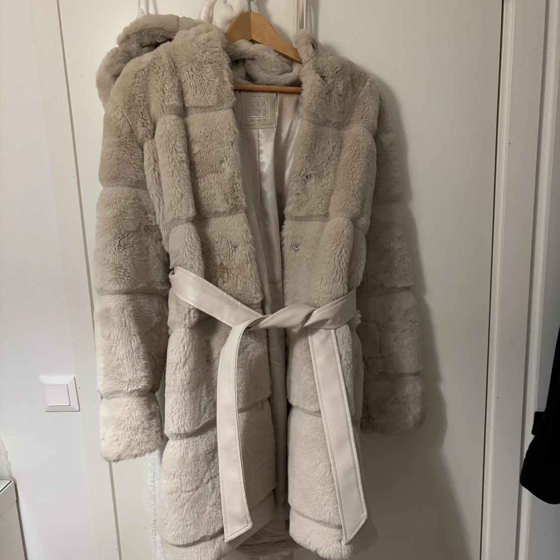 Beige pälsjacka med huva och bälte