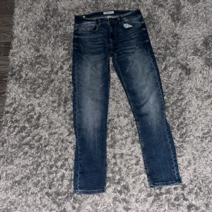 Blå jeans från Smog/Original 30/32 - Snygga blå jeans från Smog/Original i klassisk tvätt med slitningar och kontrastsömmar. Modellen har fem fickor, normal passform och raka ben. Perfekta till sneakers och hoodie för en chill look.