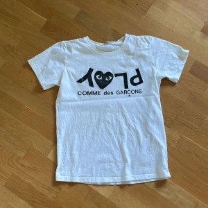 Vit Cdg-T-shirt  - Säljer denna Cdg tröja då den börjar bli lite för liten. Den är i storlek M, men sitter mer som en S. Bokstäverna är lite slitna de är därför priset är lite lägre. Hör av er vid minsta fundering!💫