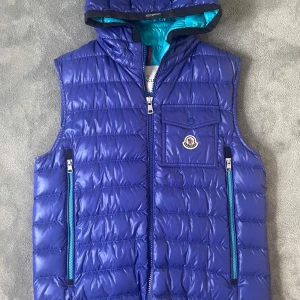 Moncler väst  - Blå ragot vadderad väst från moncler i storlek 3 som motsvarar L. Mycket sparsamt använd utan defekter. Nypris ligger på 8890kr.