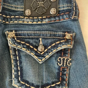 Miss Me blå bootcut jeans med brodyr - Assnygga blå jeans från Miss Me med bootcut passform. Otroligt lågmidjade! Jeansen har coola slitningar och jättesnygga detaljer. Priset beror på att dessa jeans är väldigt svåra att få tag i när det gäller små storlekar! Jag är 163 och jeansen passar mig men dem är små i storleken. (pris kan diskuteras!!)
