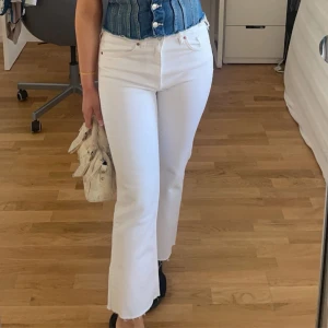 Vita cropped flare jeans - Säljer ett par vita jeans i en cropped flare model. Byxorna har en medelhög midja. Perfekta att styla med sneakers eller klackar för en clean look. Använda ett fåtal gånger.
