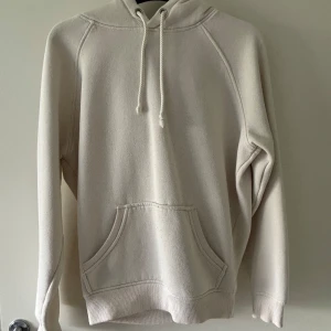 Beige hoodie från BikBok XS - Mysig beige hoodie från BikBok i storlek XS. Tröjan har huva med snörning, känguruficka framtill och är tillverkad i mjuk bomullsmix. Perfekt för chill dagar och enkel att matcha med jeans eller leggings.