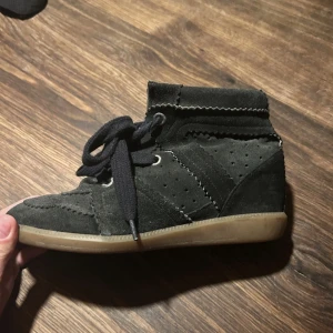 Svarta Isabel Marant bobby - KÖP HELST PÅ VINTED säljer för 2700 på vinted, INTE på plick!! Snygga svarta sneakers från Isabel Marant i mocka med perforerade detaljer och råa kanter. Skorna har snörning och en platt, ljus gummisula. Perfekta för dig som gillar en avslappnad men trendig stil.