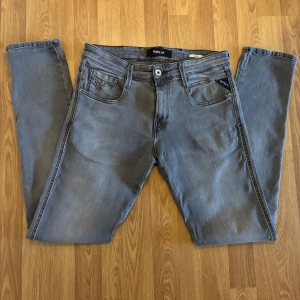 Grå Replay jeans slim fit - Snygga gråa jeans från Replay. Jeansen har en slim passform och raka ben, tillverkade i mjukt denimtyg som sitter skönt hela dagen. Perfekta för dig som gillar stilrena och moderna jeans. Skicka 10/10. Storlek W 30/32 längd. Priset är inte satt i sten så hör av er för fler frågor eller bilder. 