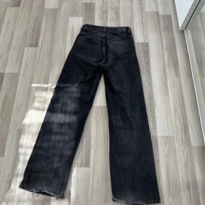 Svarta wide jeans med rå kant - Säljer ett par svarta jeans med breda ben och råa, fransiga benslut. Jeansen har klassisk femficksdesign och hög midja. Perfekta för dig som gillar en avslappnad och trendig look.