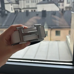 H svart och vitt skärp med H-spänne  - Snyggt H bälte i svart och vitt skinn med ikoniskt H-spänne i silver. Bältet har en stilren och klassisk design som lyfter vilken outfit som helst. Pris kan diskuteras 