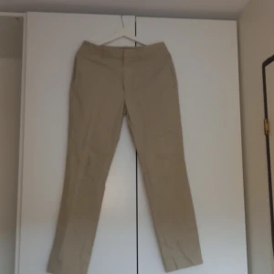 Beiga chinos från Gant W31/L32 - Snygga beiga chinos från Gant i klassisk rak modell. Byxorna har bälteshällor, framfickor och två bakfickor med knapp. Tillverkade i mjuk bomull, perfekta för en clean och stilren look. Skriv till mig för fler foton❤️