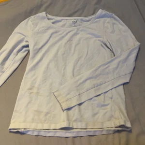 Vit långärmad tröja från 157 - Enkel och stilren vit långärmad tröja från 157. Tröjan har rund halsringning och är tillverkad i mjuk bomull, perfekt för lager-på-lager eller som basplagg. Passformen är normal och materialet känns skönt mot huden.
