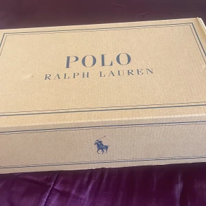 Vita sneakers från Polo Ralph Lauren - Fräscha vita sneakers från Polo Ralph Lauren med klassisk broderad logga på sidan. Skorna har en stilren design med snörning och är tillverkade i canvas med detaljer i syntet. Perfekta för en clean och sportig look.