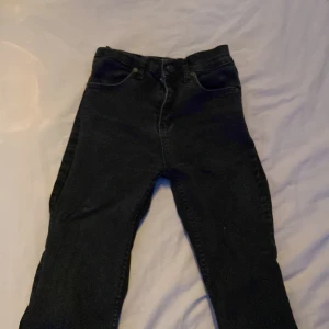 Svarta jeans med slits och rå kant - Säljer ett par svarta jeans med hög midja och skinny fit. Jeansen har slits nertill på benen och rå, fransig kant för en trendig look. Klassisk femficksmodell och dragkedja fram. Perfekta för dig som gillar en edgy stil.