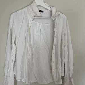 Vit skjorta från Gina Tricot - Klassisk vit skjorta från Gina Tricot i storlek S. Skjortan har lång ärm, krage och knäppning framtill. Tillverkad i ett tunt och mjukt material som känns skönt mot huden. Perfekt att styla lager på lager eller bära som den är.